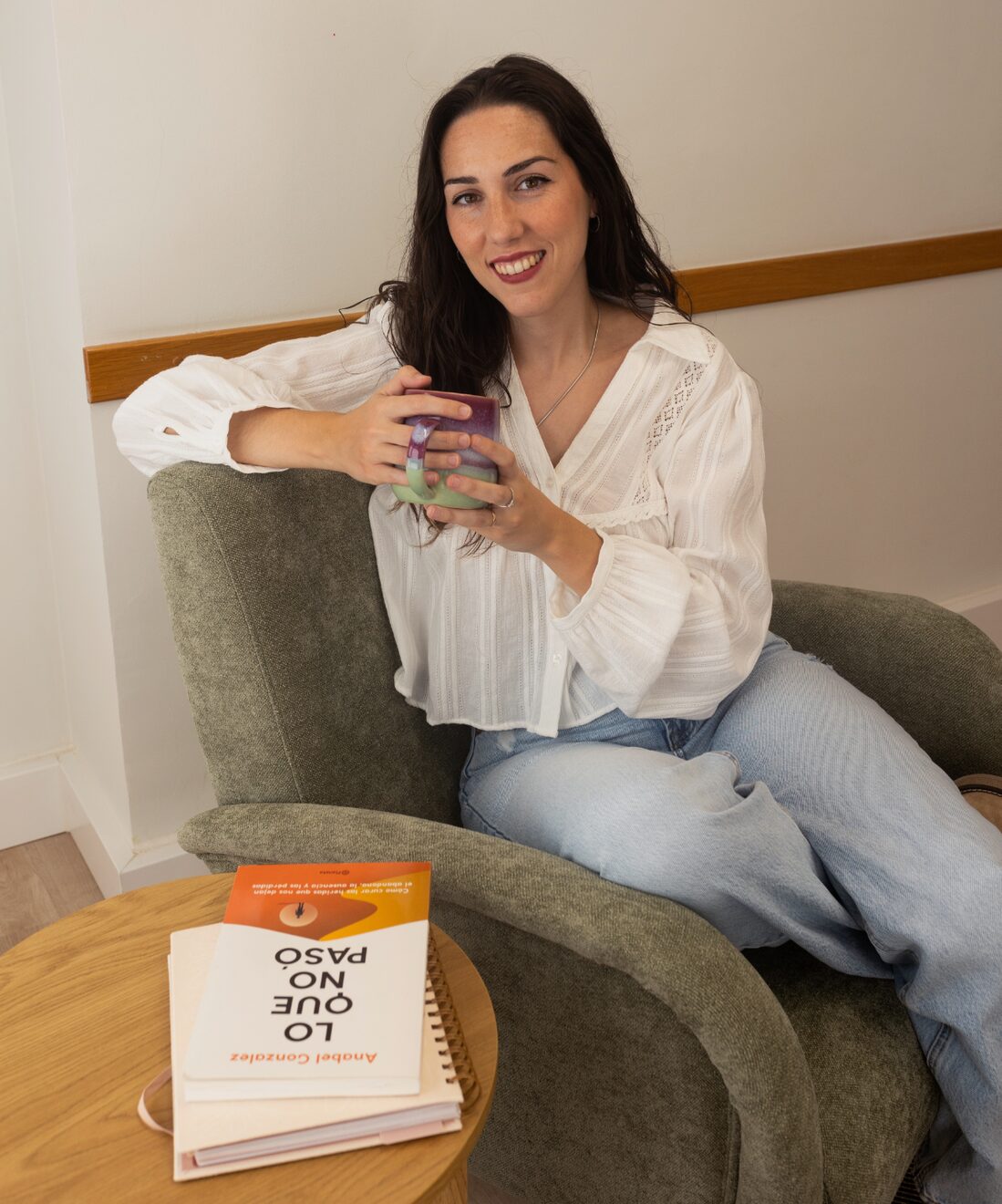 Laia sentada en el sillón de su consulta con una taza en las manos